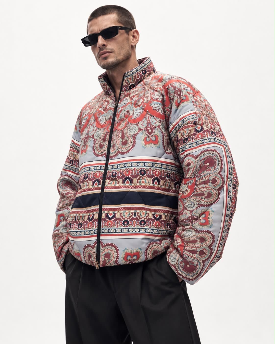 Model wearing the paisley puffer jacket with black trousers and sunglasses, full length