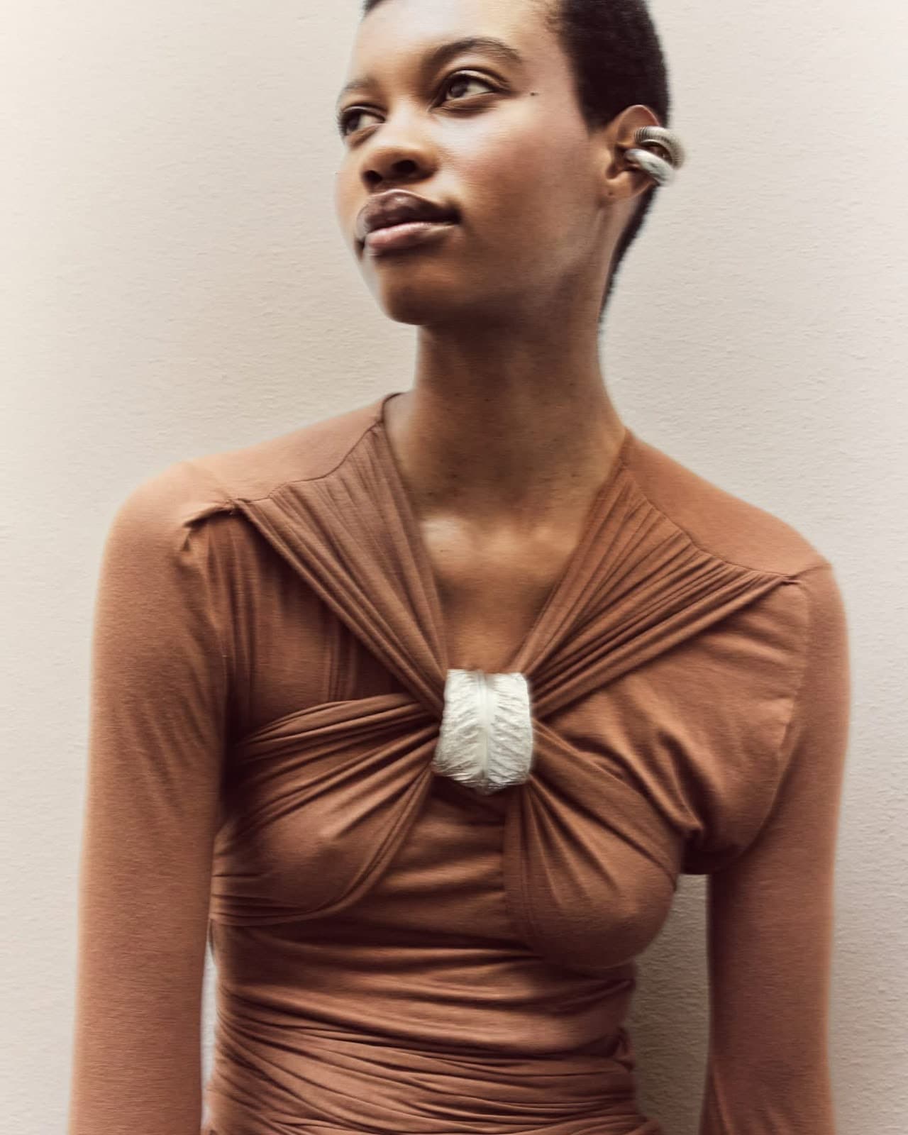 Close-up of the model in the camel cross-draped Inova dress, showing the V neckline