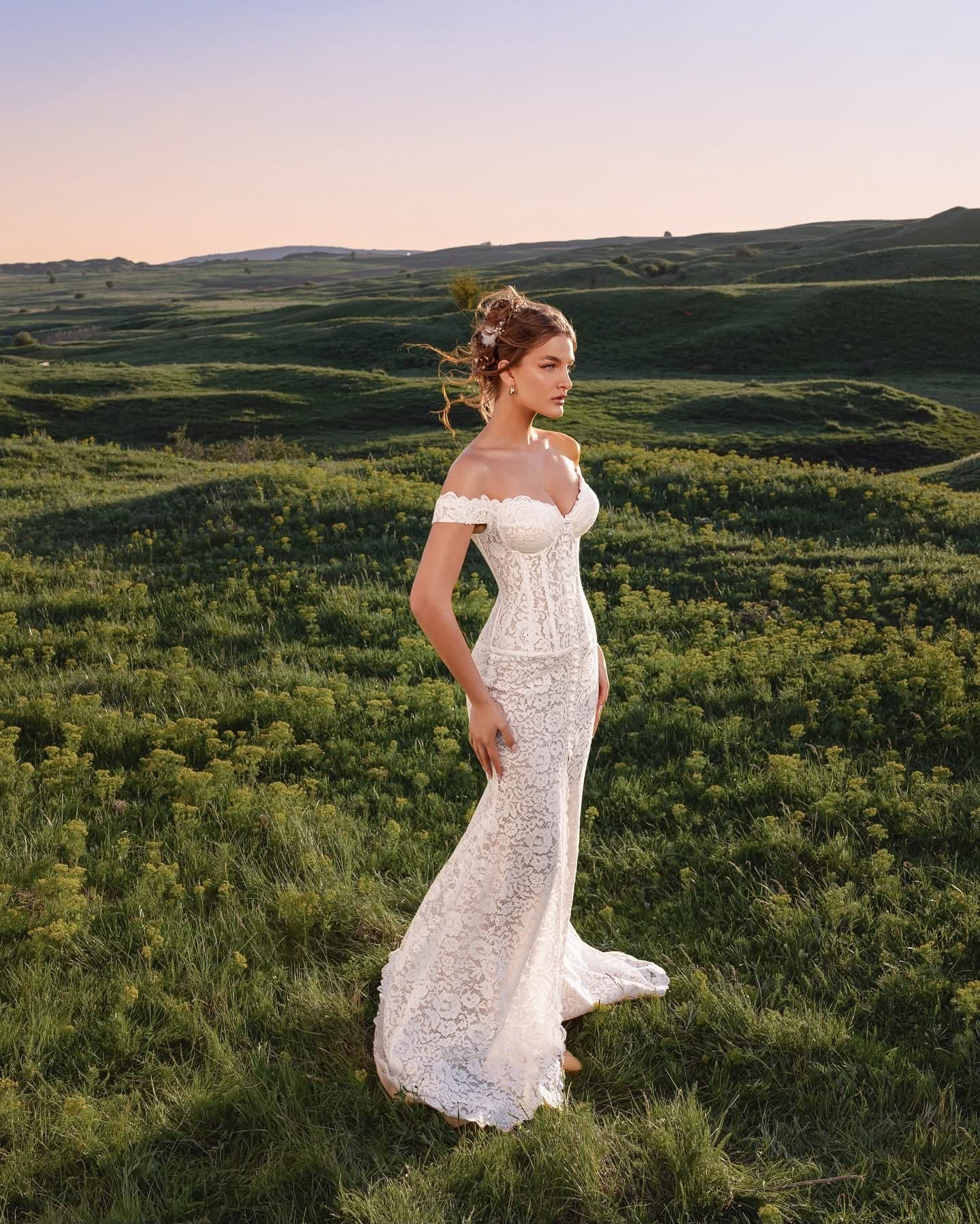 Bride in the Sirène Dentelle Gown, side view, on a hillside at dusk