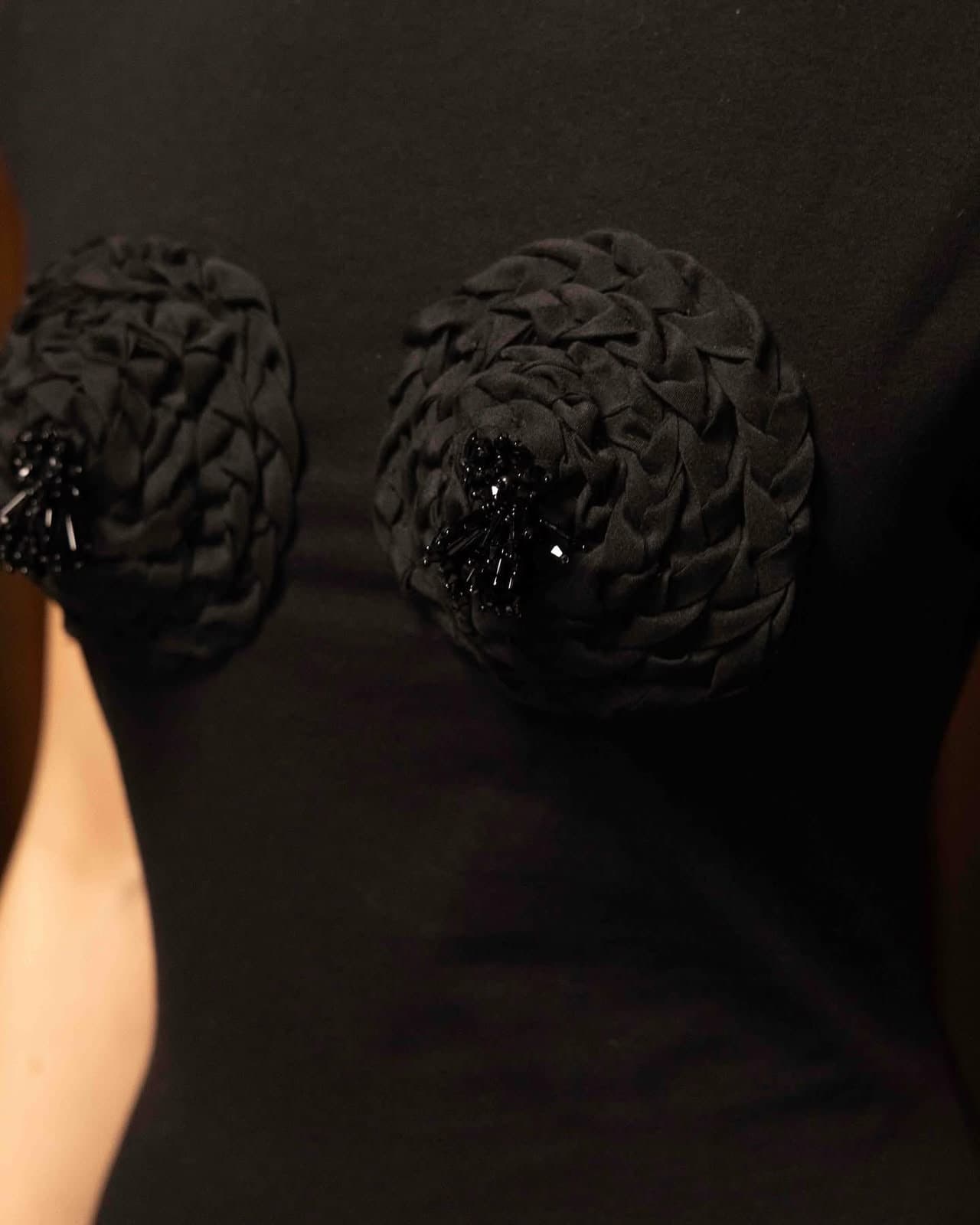 Close-up of the two fabric rosettes at the bust of the black gown