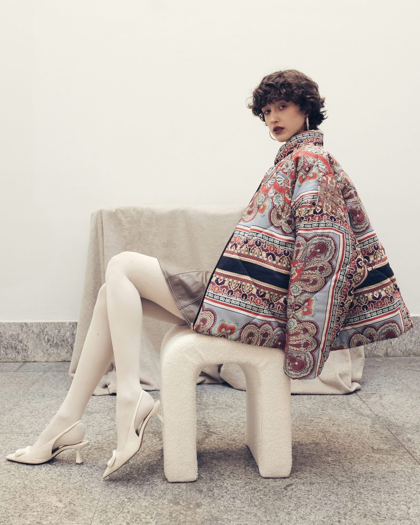 Model seated wearing the oversized paisley puffer jacket, full length