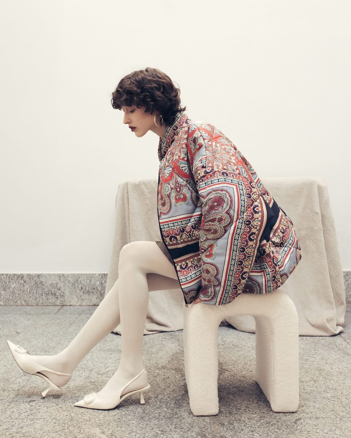 Model seated in the paisley puffer jacket, side view showing the dropped shoulder and sleeve